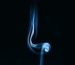 Captivating abstract image of blue smoke swirling against a black backdrop.