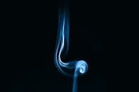 Captivating abstract image of blue smoke swirling against a black backdrop.