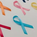 Various colored ribbons representing different cancer awareness causes on a white surface.